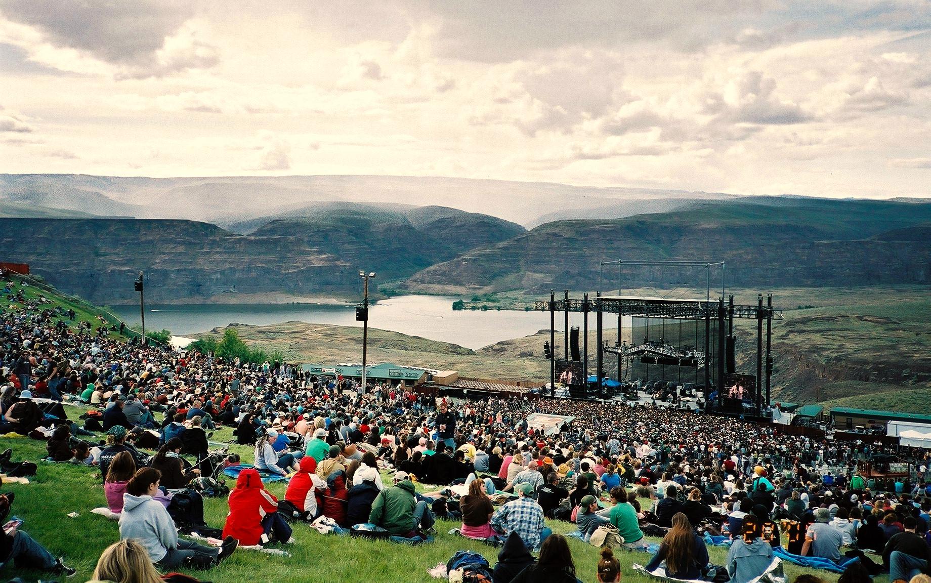 A festival crowd on the Gorge Amphitheatre's lawn, with the stage and the Columbia River canyon beyond
